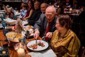 Um casal mais velho ri na District Winery em Washington DC enquanto o marido rouba comida de sua esposa de brincadeira durante a recepção.